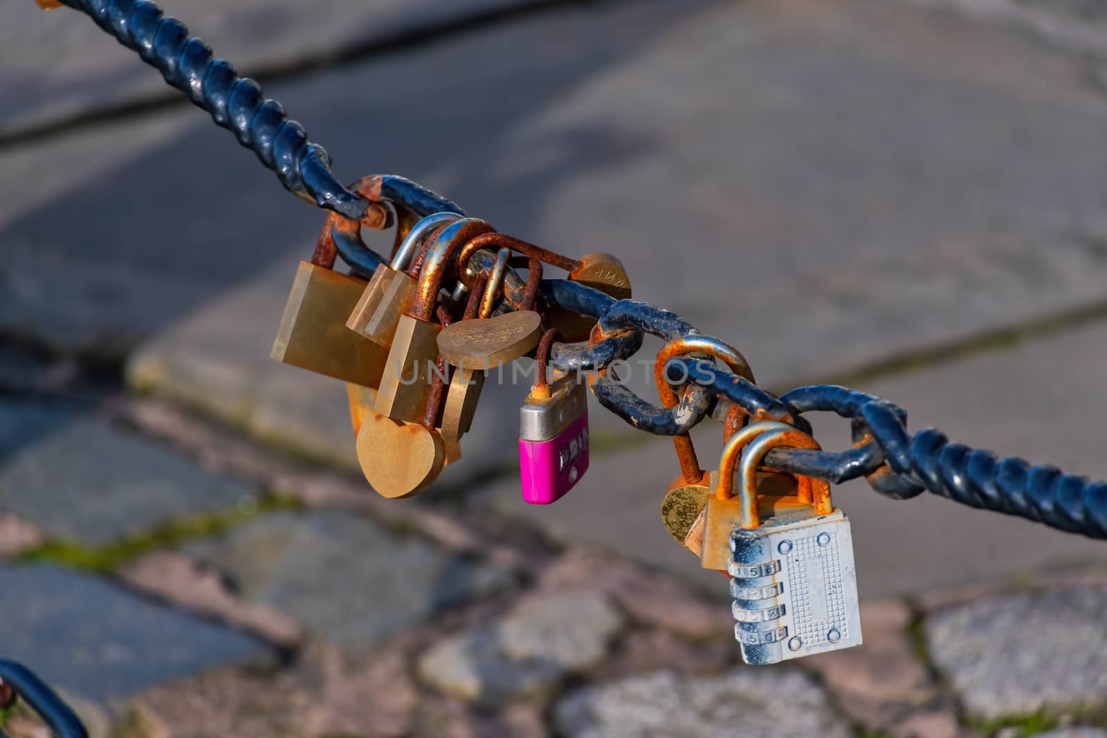 Old rusty Love Lock padlocks attached to a chain fence