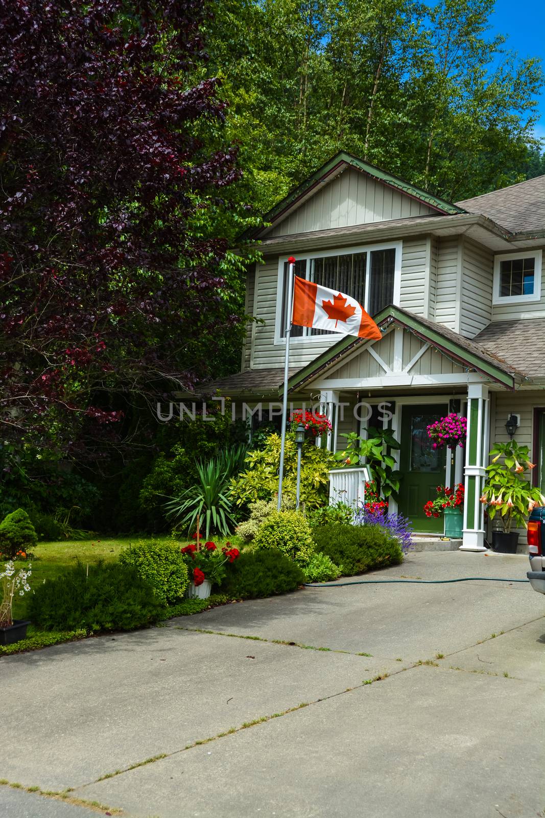 Main entrance of family house with canadian flag in front. Fragment of residential house with concrete driveway