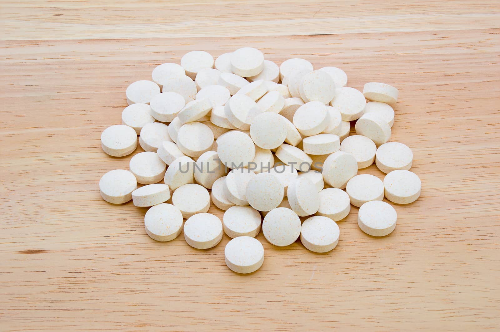 A pile of vitamin tablets on a wooden background