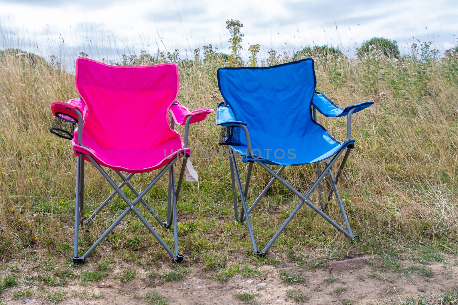 Pink and blue folding camping chairs in a field