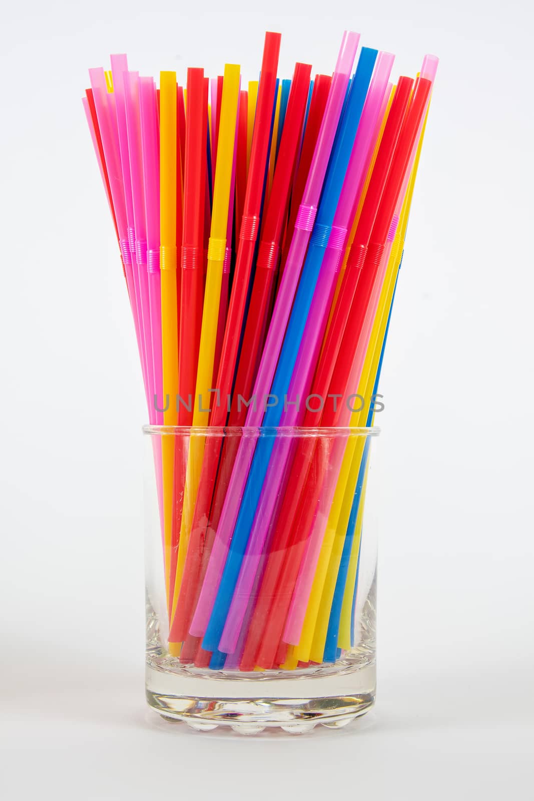 Multi coloured plastic drinking straws in a glass