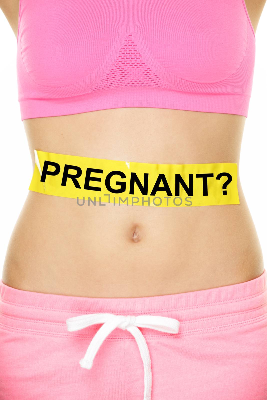 Midsection of young woman with pregnant written on yellow sign. Mixed race female is showing concept of doubt. She is standing against white background.