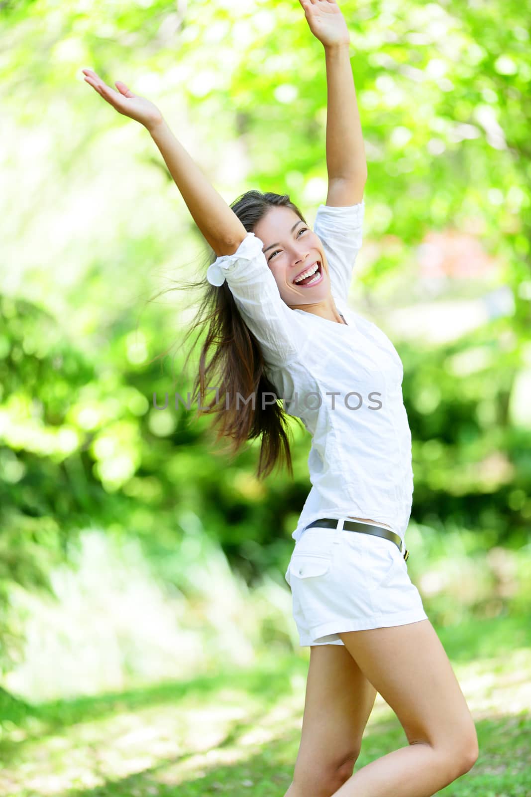 Excited Woman With Arms Raised Standing In Park by Maridav