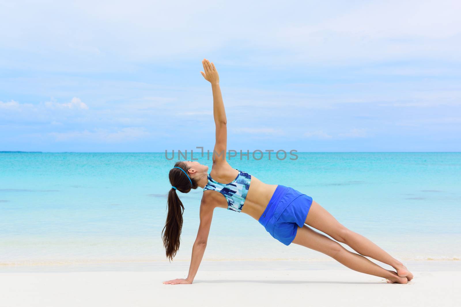 Fitness woman strength training her body core muscles with yoga pose. Athlete planking on one arm doing side plank and hip lift.