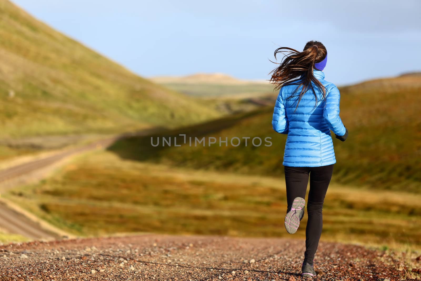 Running woman on trail run doing fitness exercise in spring autumn mountains. Person training outside in cold weather in blue sportswear. by Maridav