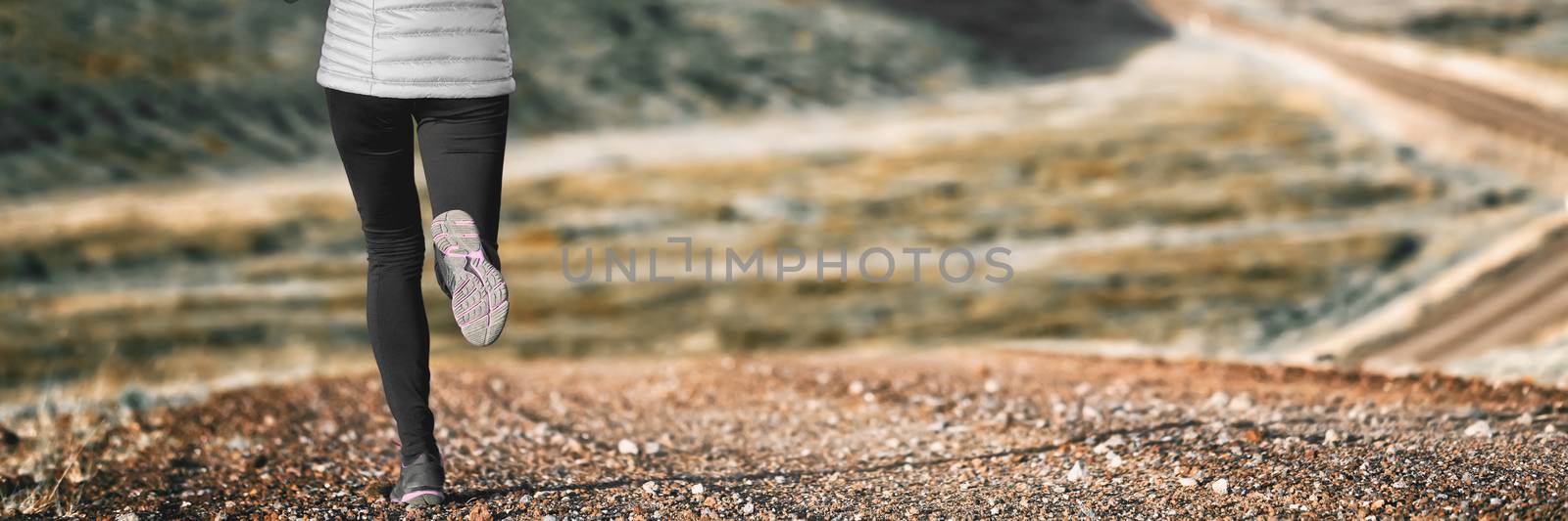 Trail runner athlete girl running in winter outdoors with warm tights and running shoes. Banner panorama of legs. Healthy active lifestyle.