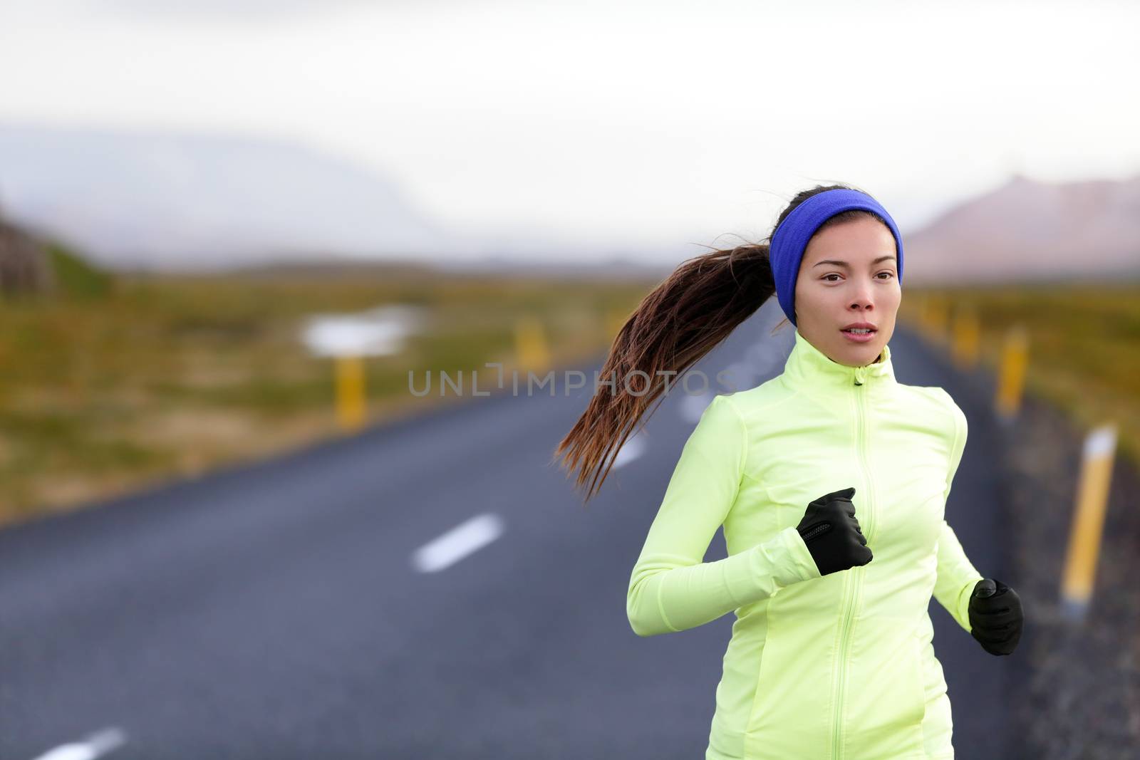 Female runner running in warm clothing for winter and autumn outside. Woman runner training in cold weather living healthy active lifestyle.