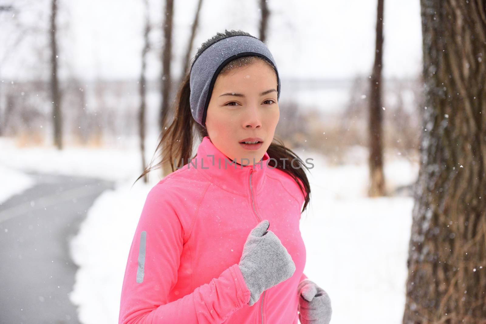 Asian woman running in winter gloves and headband by Maridav