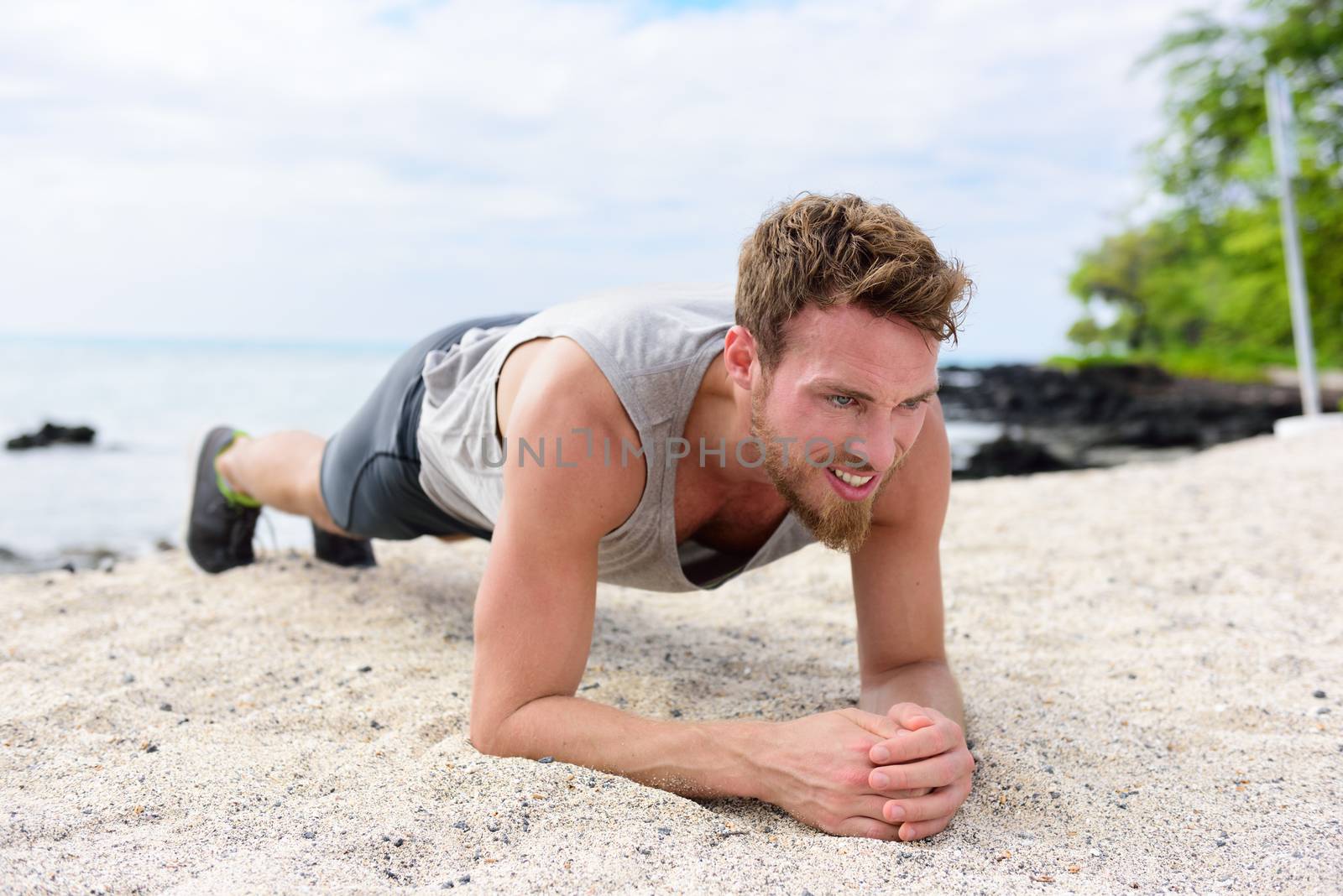 Crossfit training fitness man doing plank core exercise working out his midsection muscles. Fit athlete fitness cross training planking exercising outside in sand on beach. by Maridav