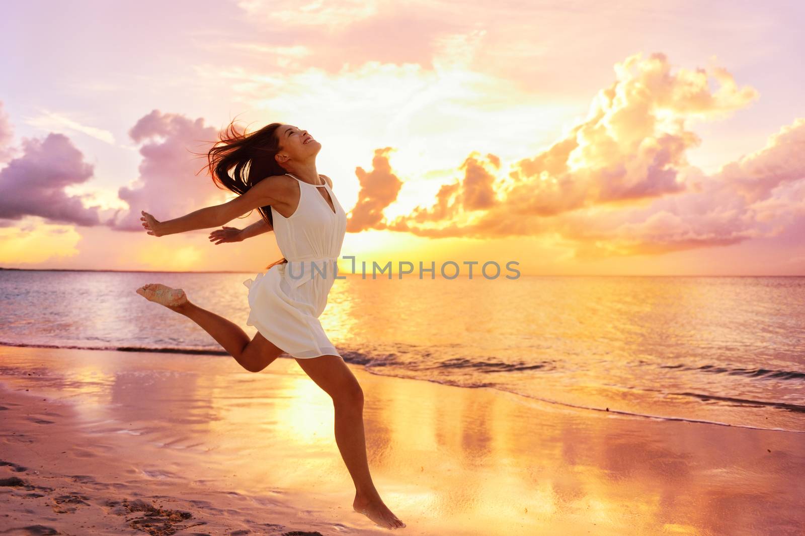 Freedom wellness well-being happiness concept. Happy carefree Asian woman feeling blissful jumping of joy on peaceful beach at sunset. Serenity, relaxation, mindfulness, stress free concepts.