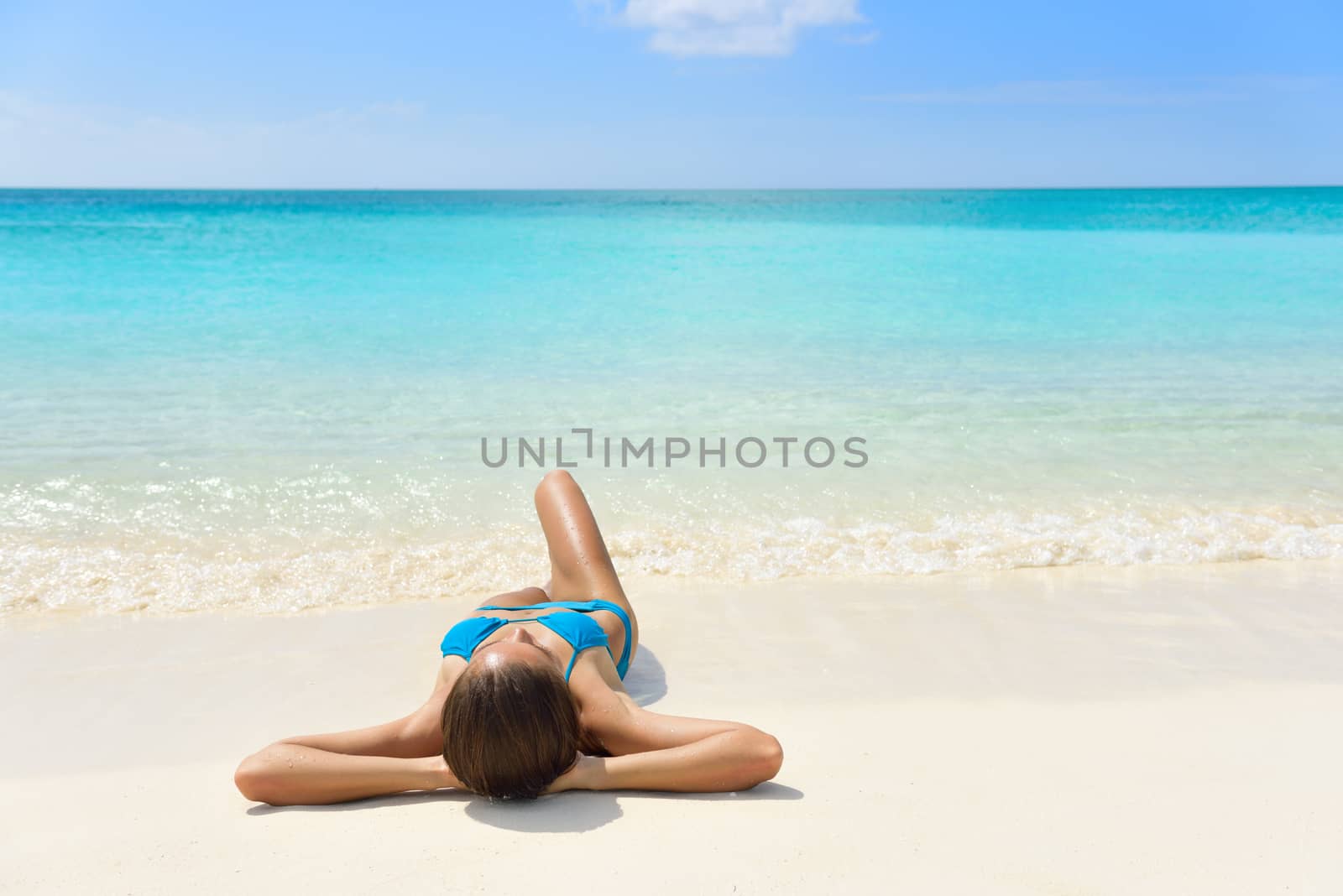 Tropical Caribbean beach vacation - suntan relaxation woman. Bikini girl lying down relaxing on white sand exotic destination sleeping and sunbathing during summer holidays. by Maridav