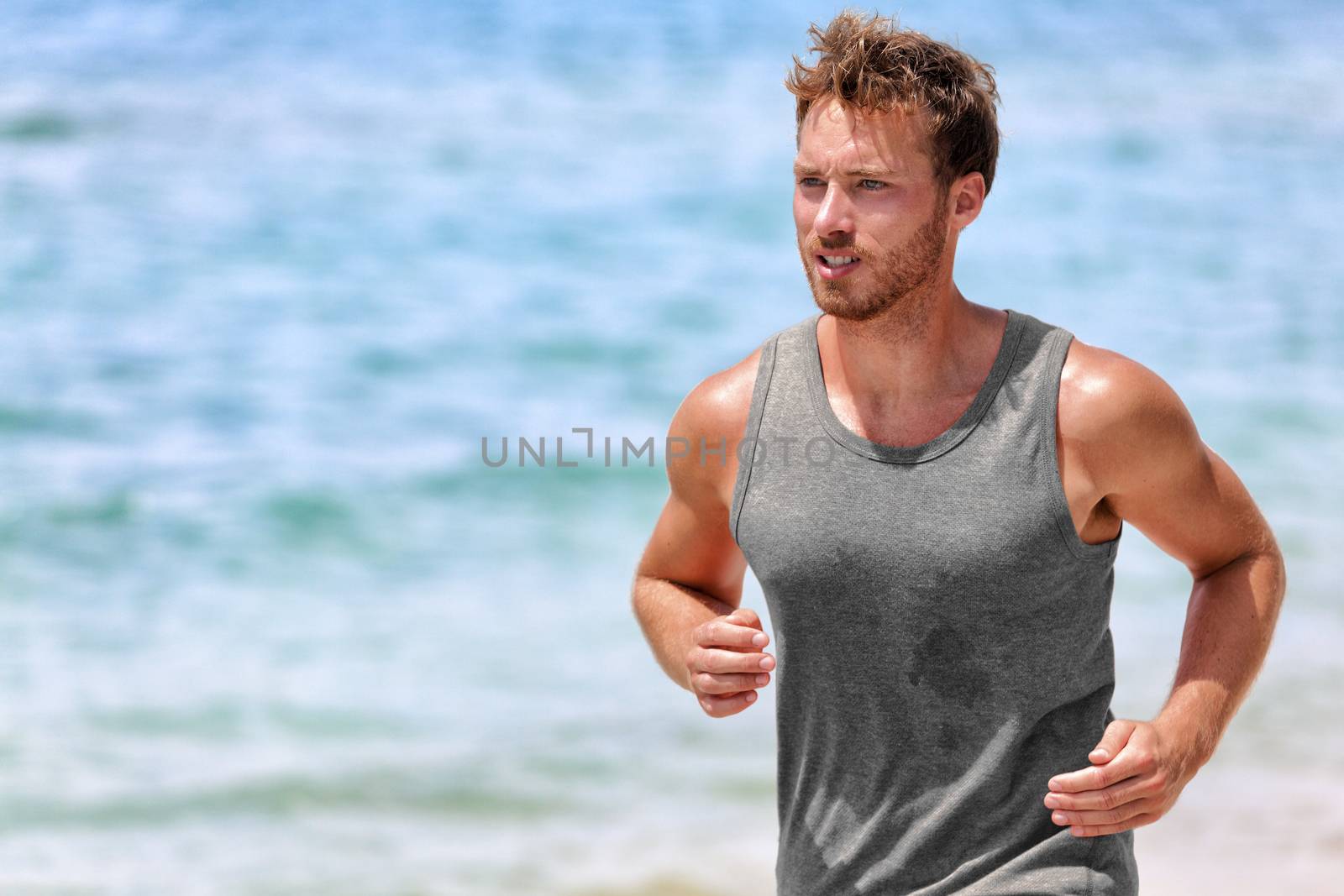 Active runner sweating running on summer beach by Maridav