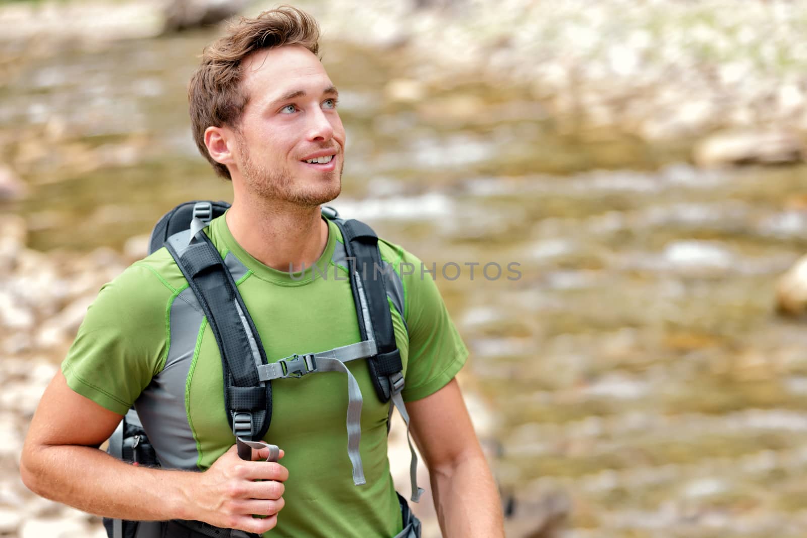 Happy hiker hiking in nature in clean river water. Aspiration young Caucasian man walking in summer nature environment with backpack. Hope, adventure travel or active lifestyle concept.