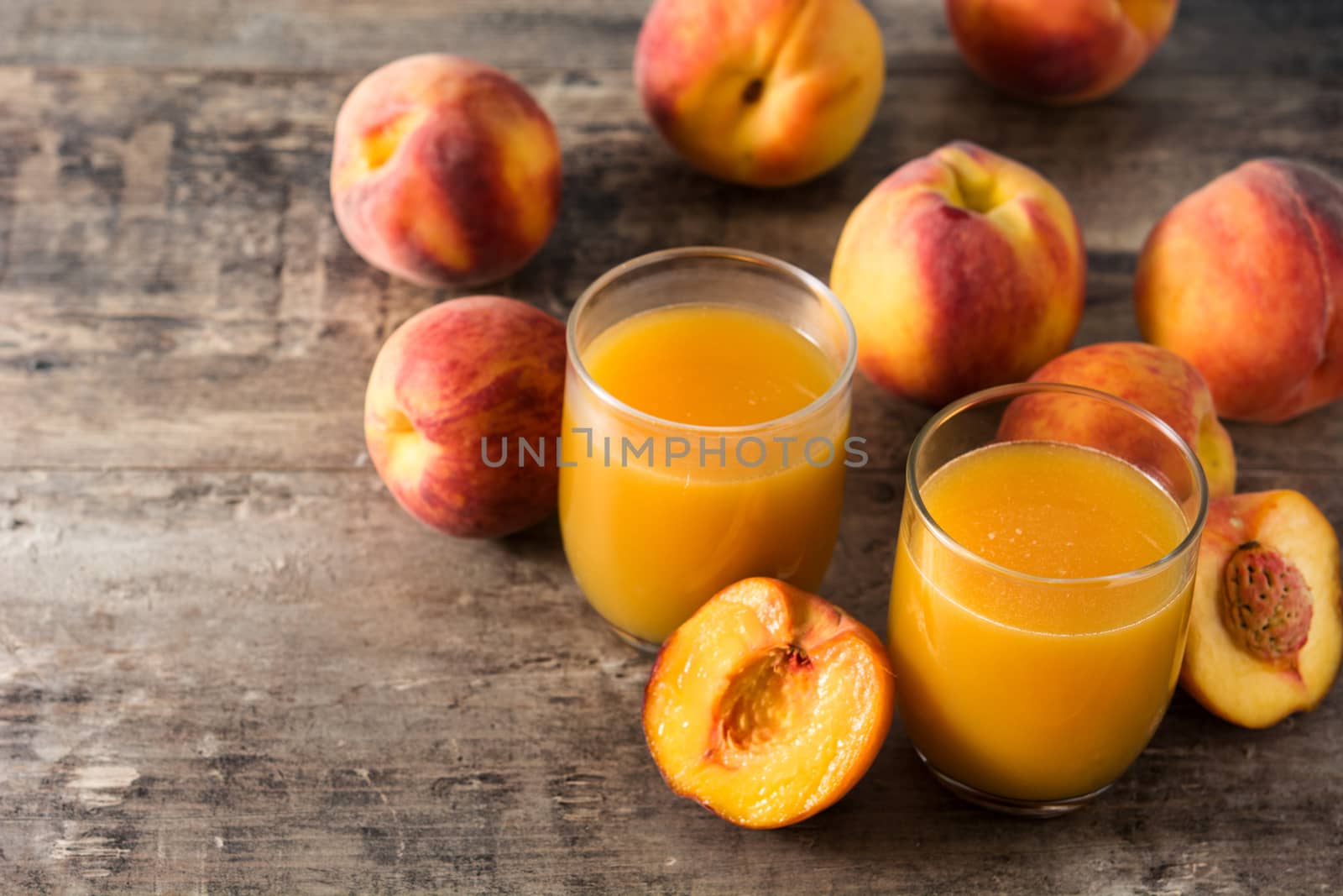 Natural peach juice in glass on wooden background