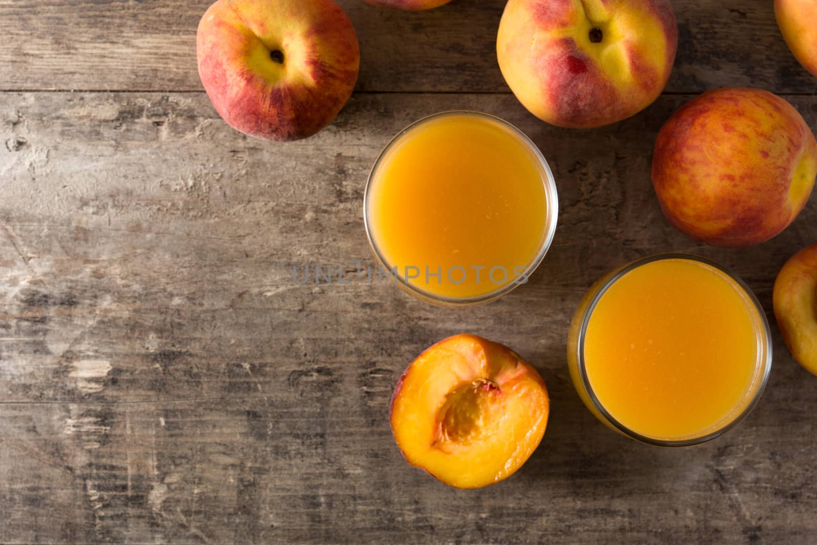 Natural peach juice in glass on wooden table top view copy space by chandlervid85
