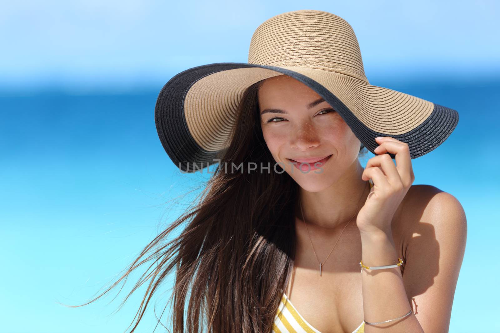 Asian woman wearing fashion straw beach hat for skin care sun protection. Face skincare beauty concept. Beautiful Chinese Caucasian mixed race young adult girl portrait on summer vacation travel.