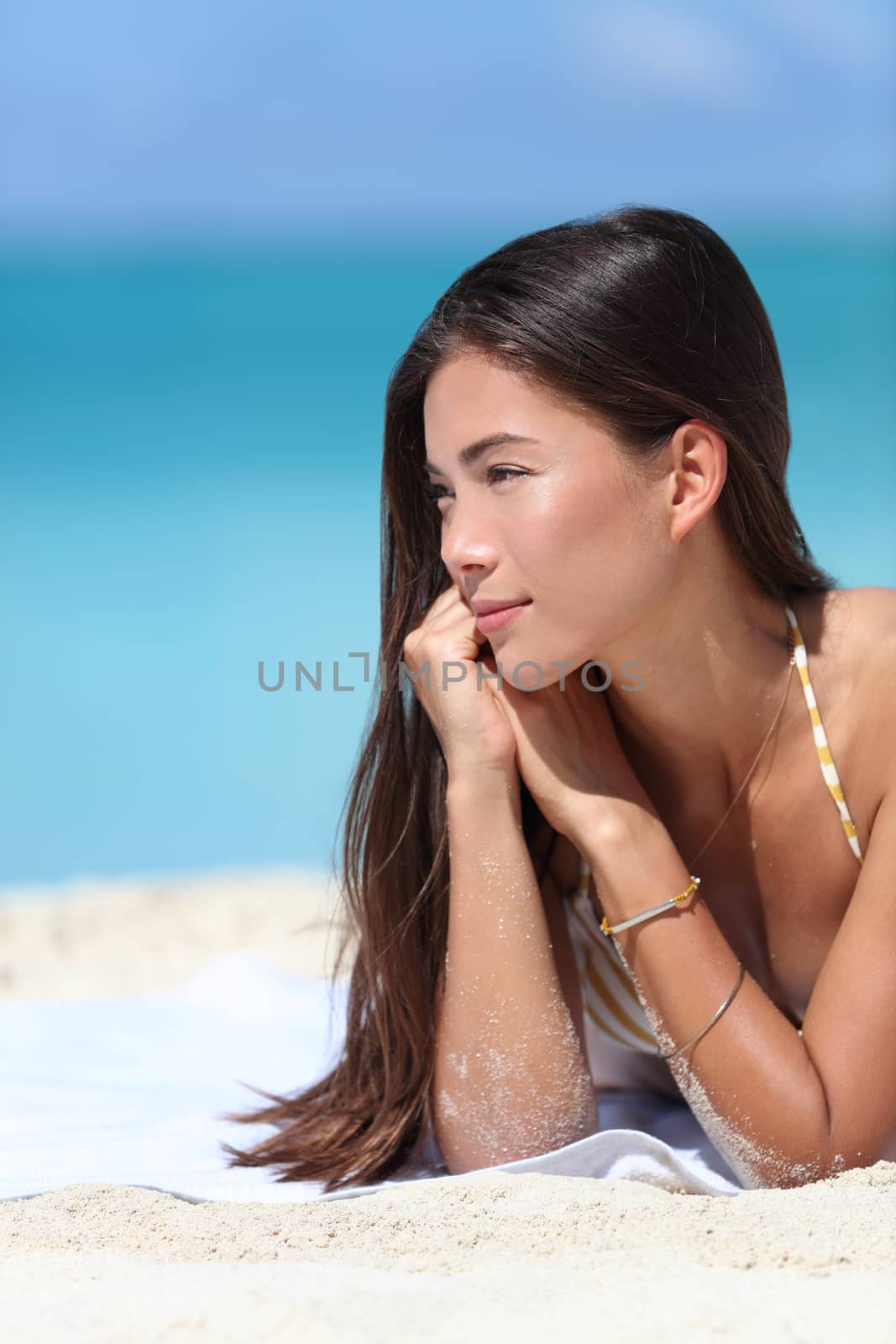 Asian beauty woman relaxing on beach during summer vacation travel. Face closeup of Chinese Caucasian mixed race fashion model posing with bracelets and sun care makeup for skincare concept.