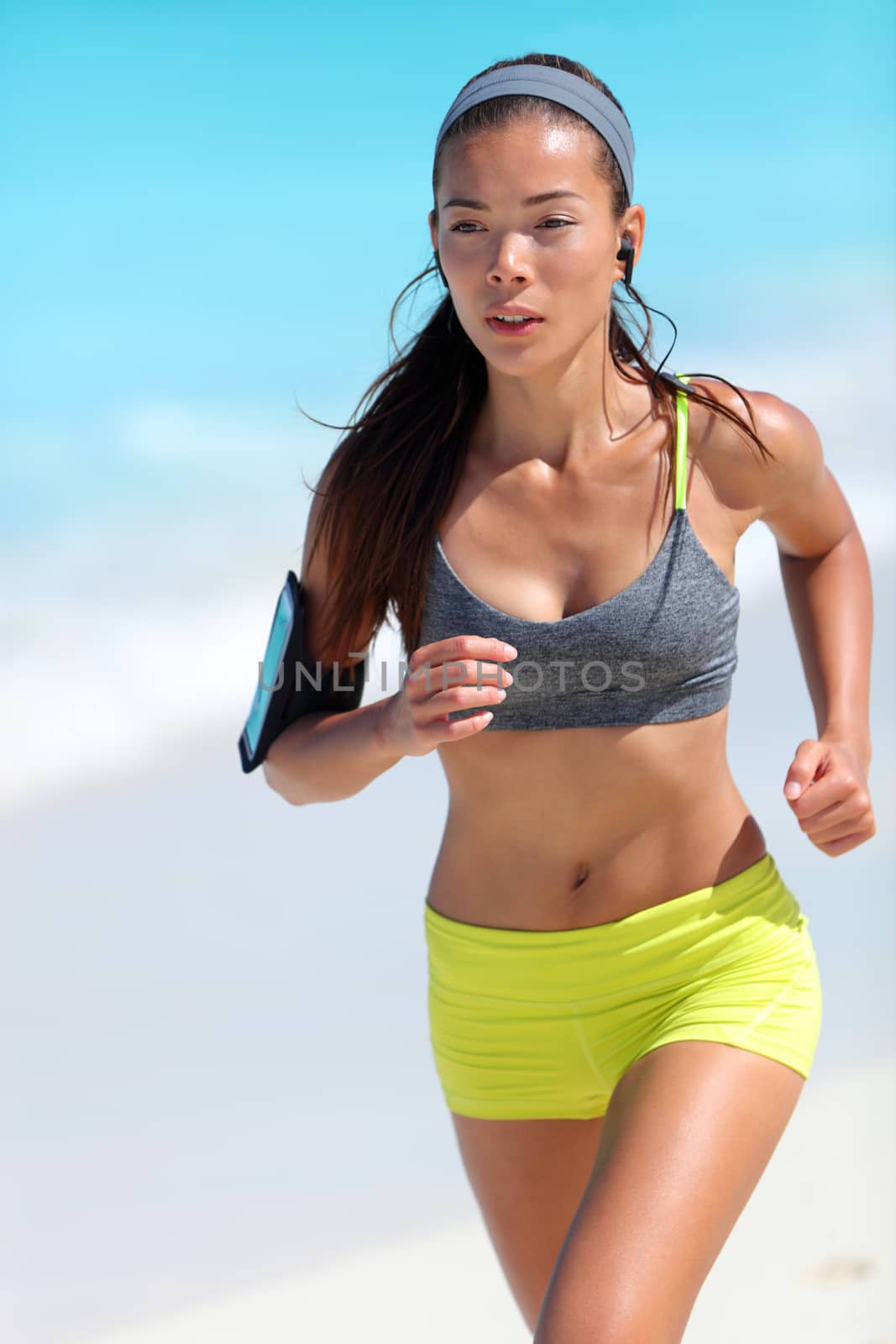 Young fit Asian woman runner running on beach by Maridav