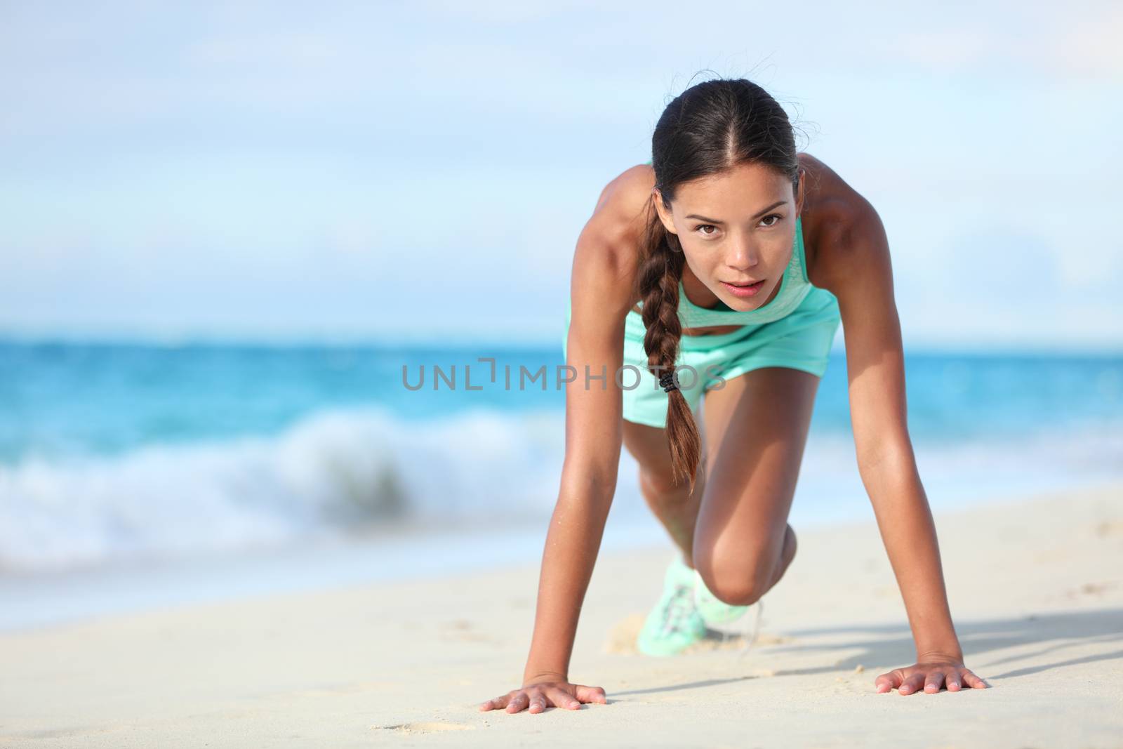 Fitness athlete working out body core with bodyweight exercises. Strong fit woman training cardio and exercising abdominal muscles with mountain climber workout exercise on beach.