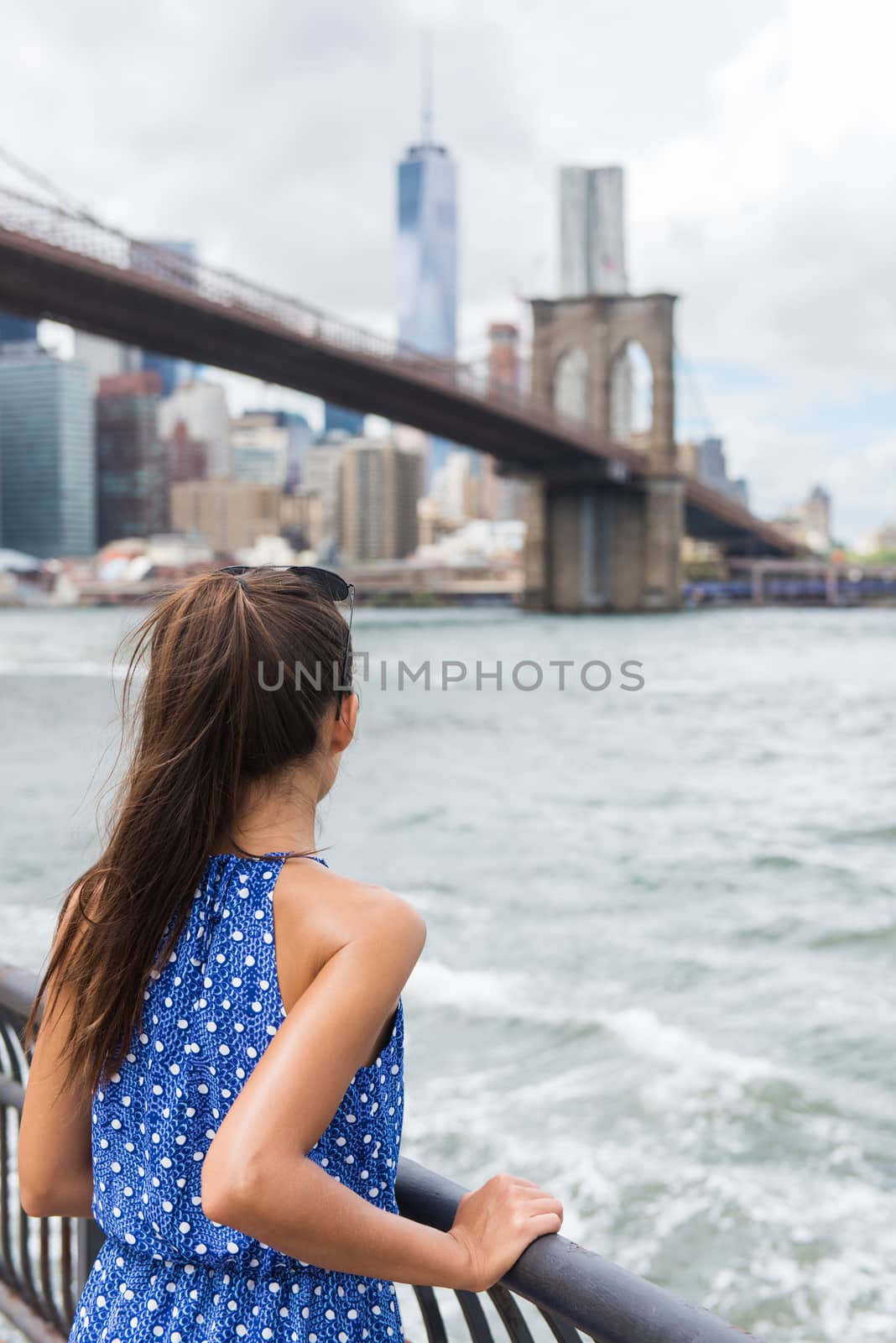 Woman looking at Brooklyn bridge and New York skyline on summer travel by Maridav