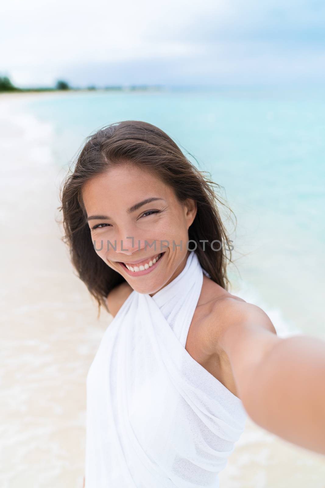 Selfie of beautiful Asian mixed race woman on beach wearing white cover-up by Maridav