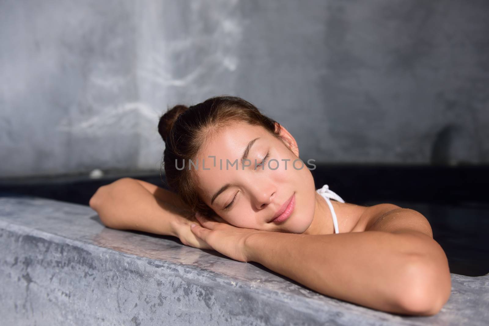 Beautiful young woman relaxing in jacuzzi hot tub at spa. Attractive female tourist is enjoying in water. Smiling woman with eyes closed is pampering herself during vacation.