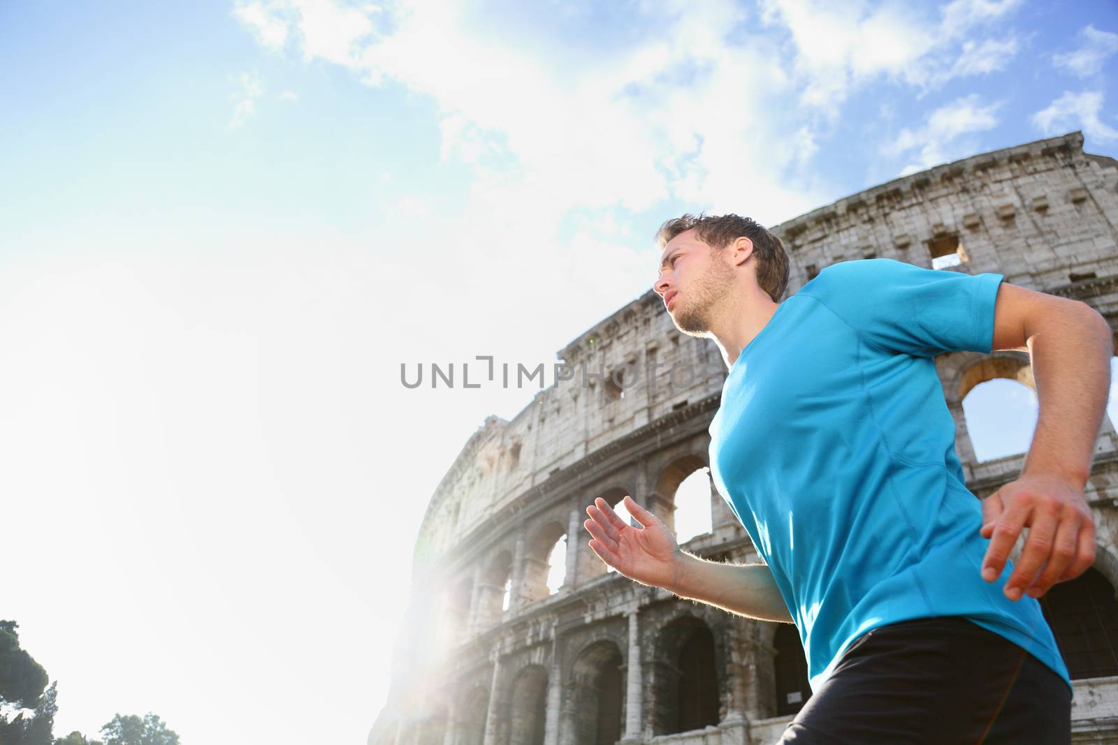 Running male runner jogging against Colosseum. Man athlete  on run confident in sportswear. Young man is exercising on sunny day living healthy active lifestyle in Rome, Italy.