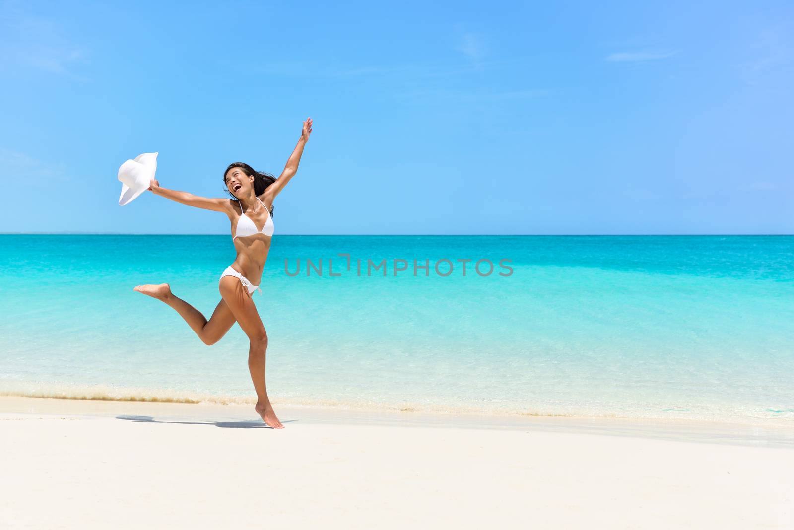 Happy bikini woman jumping of joy on white beach by Maridav