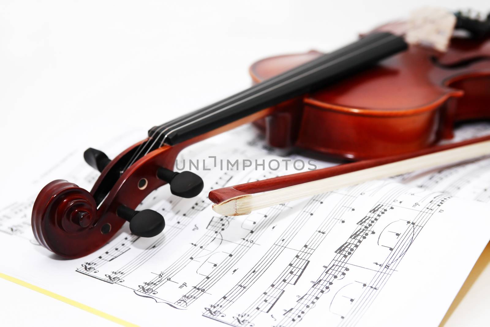 Nice violin and bow on music book on white background