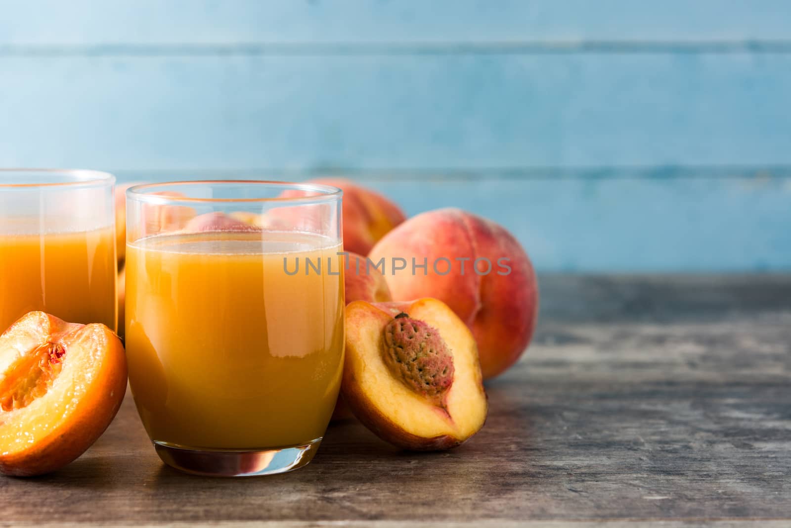 Natural peach juice in glass on wooden background