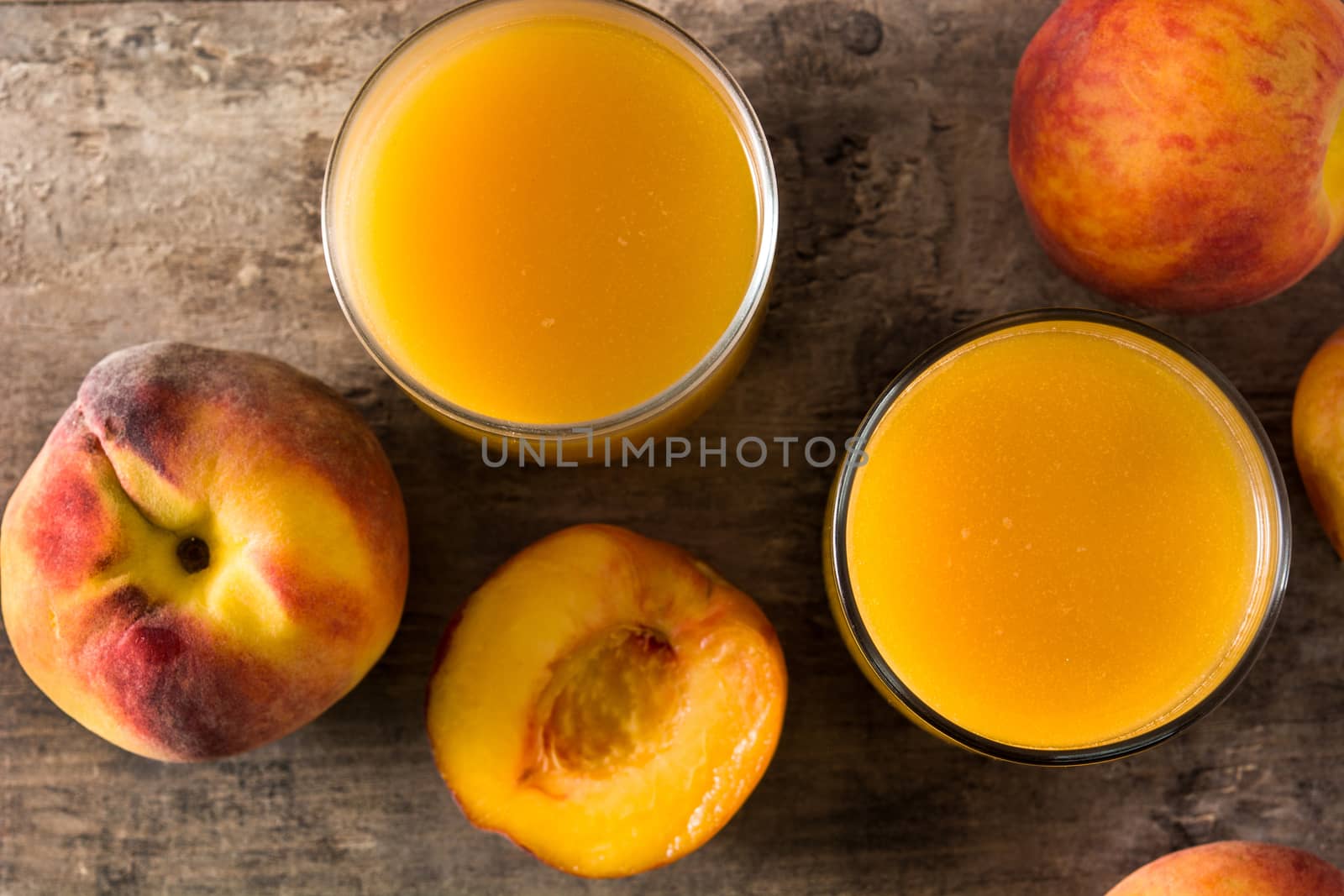 Natural peach juice in glass on wooden table top view by chandlervid85