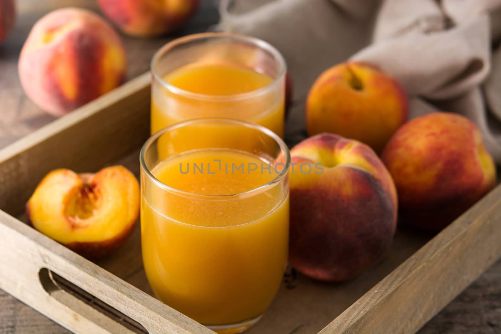 Natural peach juice in glass on wooden table by chandlervid85