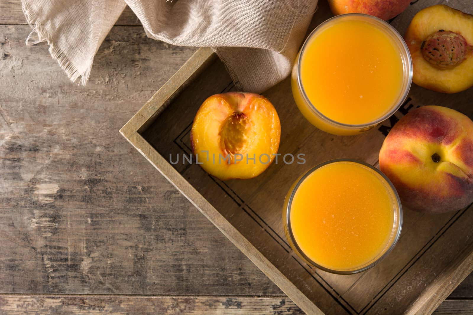 Natural peach juice in glass on wooden table. Top view copy space by chandlervid85
