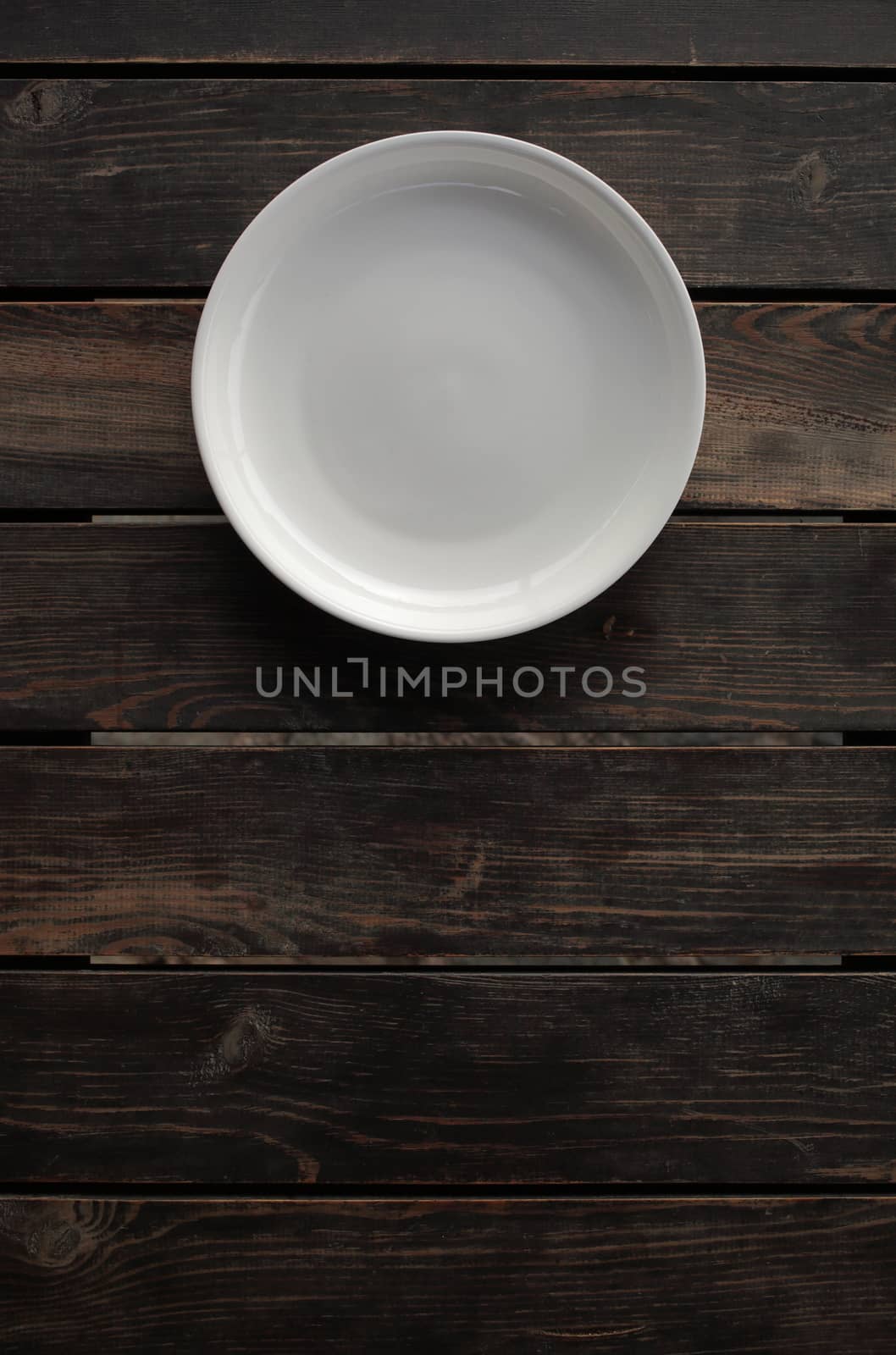Empty white plate on a wooden loft table. High-quality photo