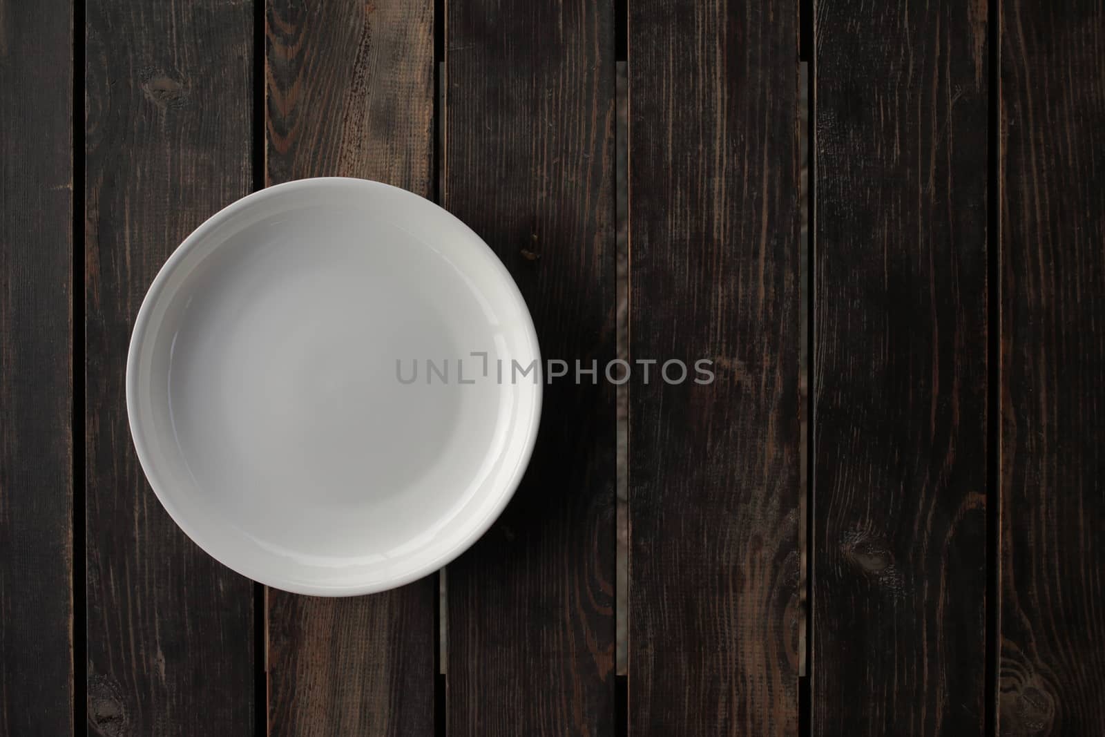 Empty white plate on a wooden loft table by selinsmo