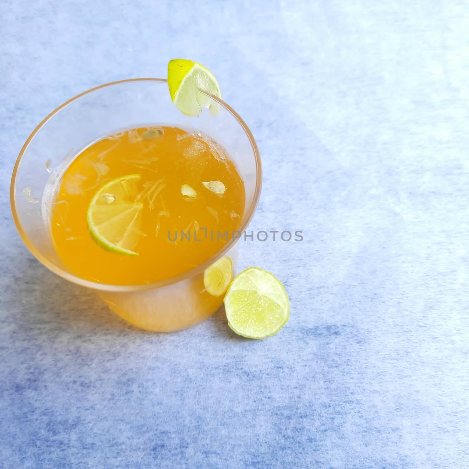 Lemon juice in glass with added orange syrup and ice cubes and slice of lemon inside and outside of glass placed beautifully in white background by AnithaVikram