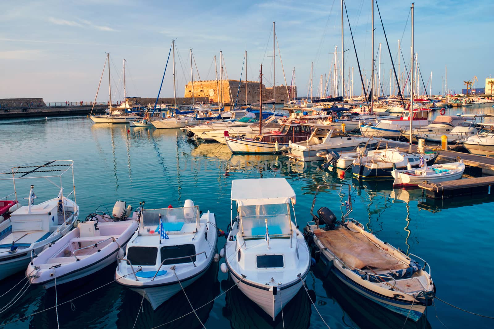 Venetian Fort castle in Heraklion and moored fishing boats, Crete Island, Greece on sunset