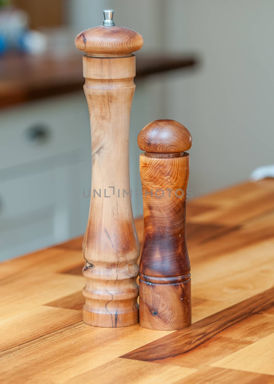 wooden salt and pepper grinders on a wood table top by sirspread