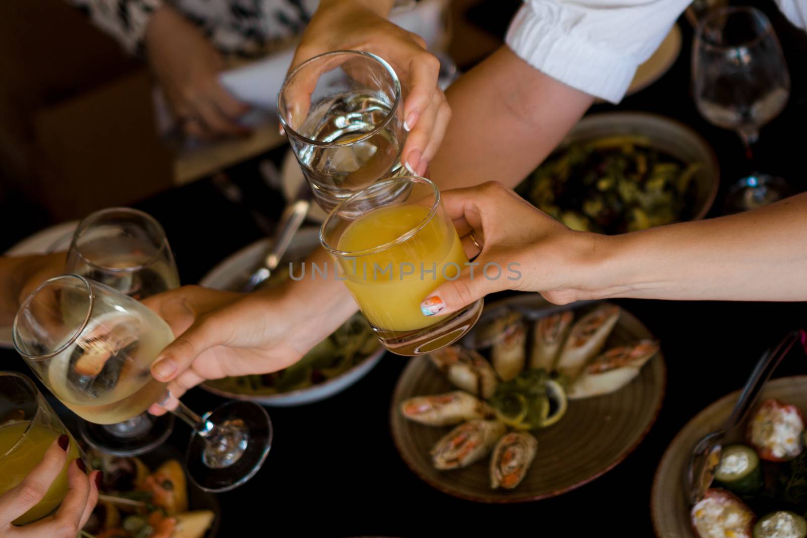 Group of friends enjoying appetizer in bar - Young people hands cheering with wine and tropical fruits cocktails