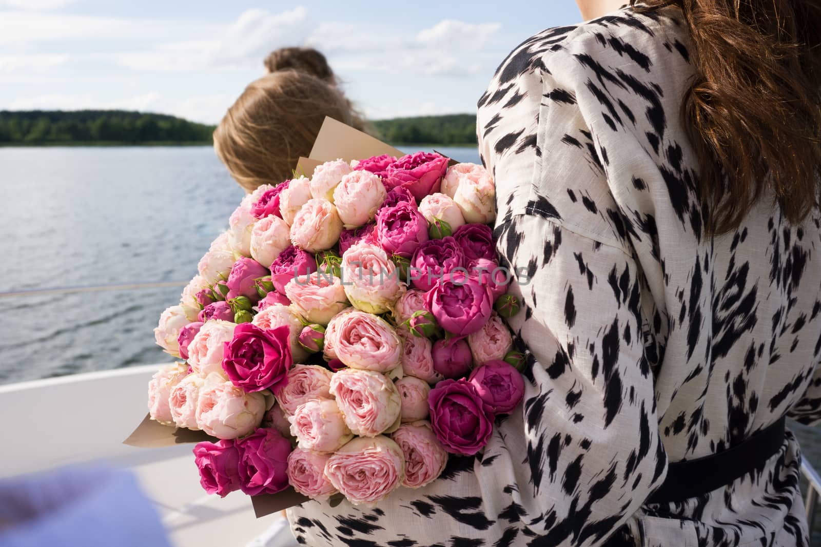 A young girl with a bouquet of bright flowers on a cruise ship - sea on background