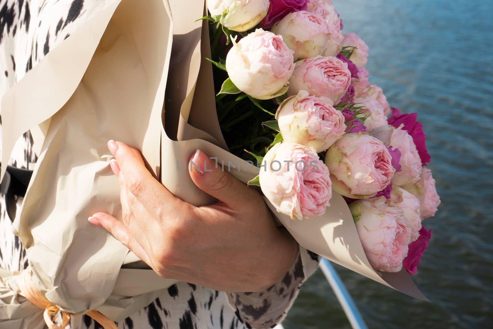 A young girl with a bouquet of bright flowers on a cruise ship - sea on background