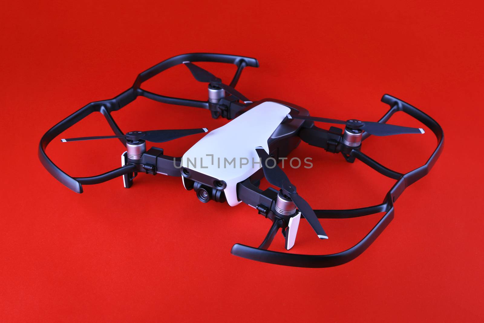 Uav drone copter isolated on white background, close-up. Small drone quadrocopter with propeller protection on a red background. Safe drone flight. Unmanned aerial vehicle on a red background.