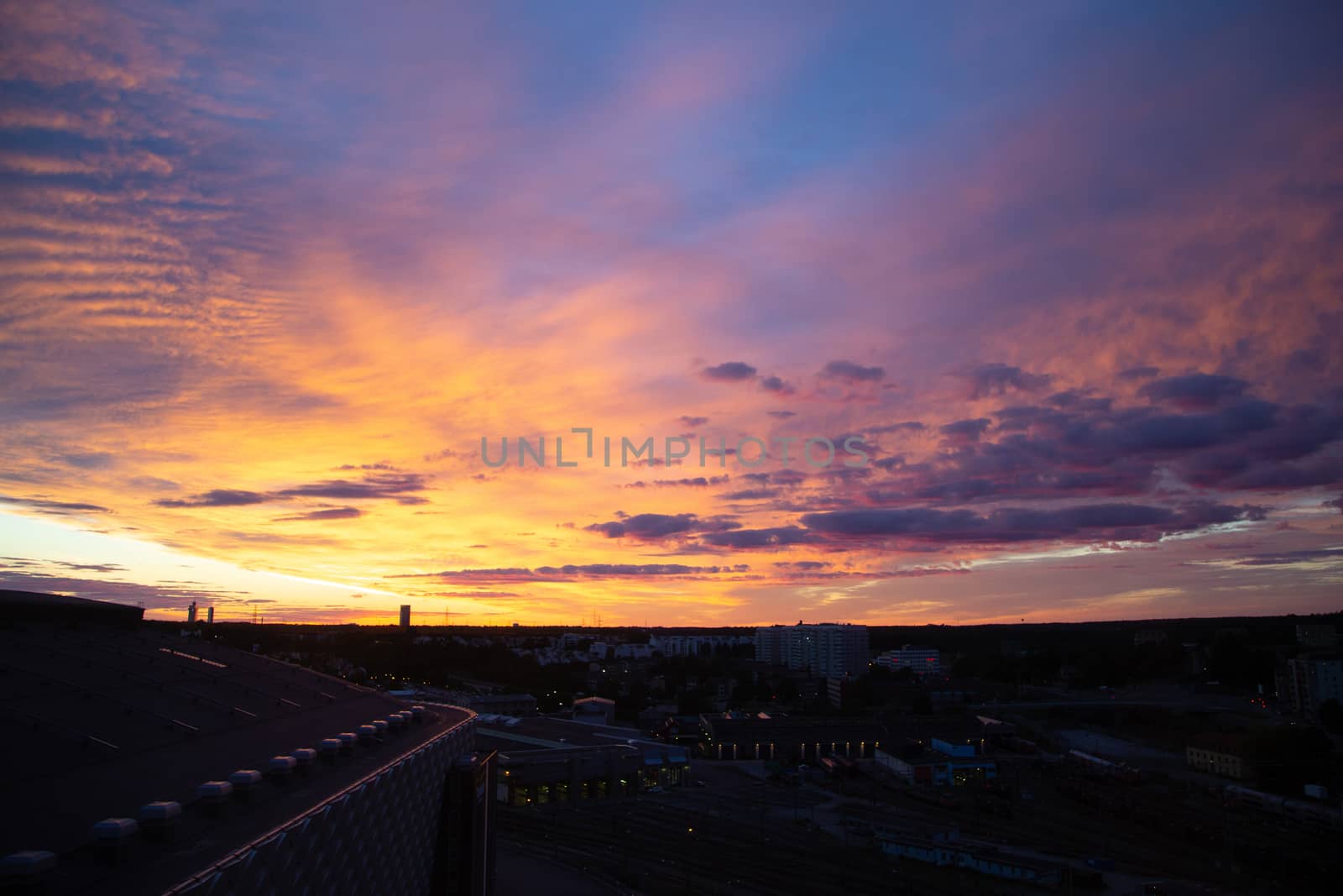 Bright sunset over the European city. View from the roof of a high-rise building. Panorama of the night city.