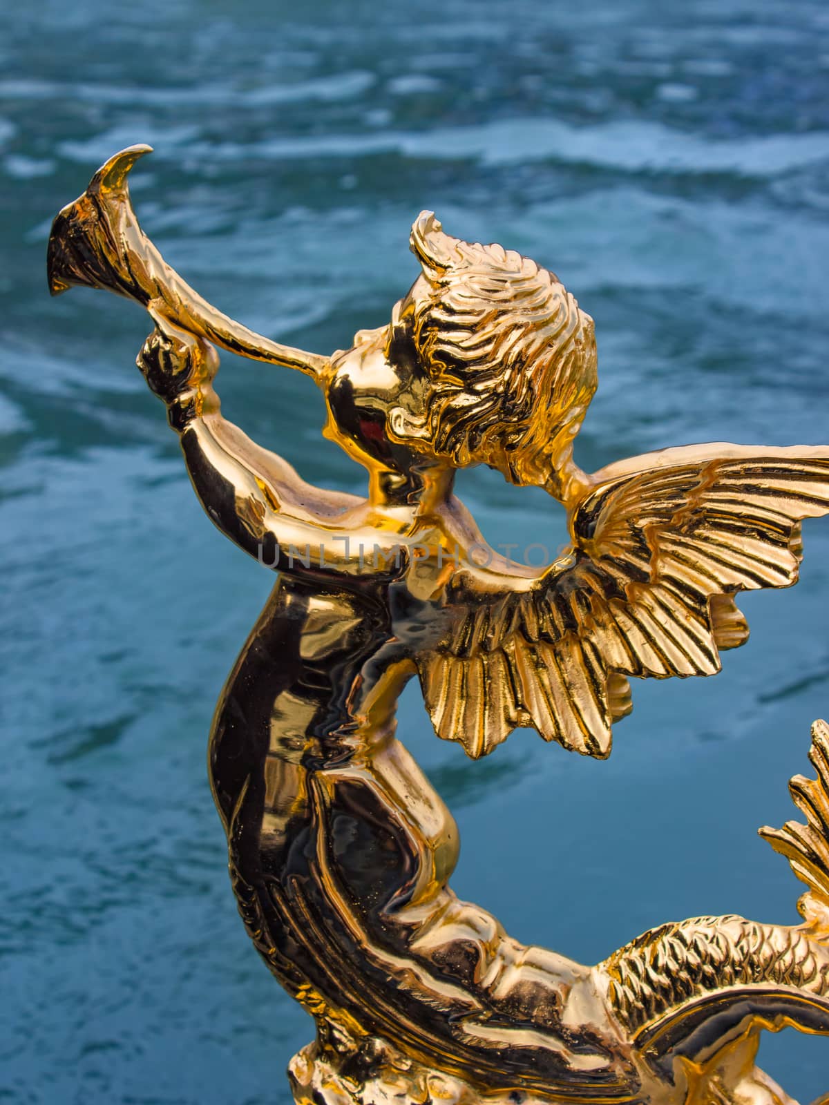 Gold figure of an angel on a gondola. Traditional symbol of Italy on gondola, made by golden statue as a shape of singing angel. Gold figurine angel as part of the gondola decor in Venice, Italy.