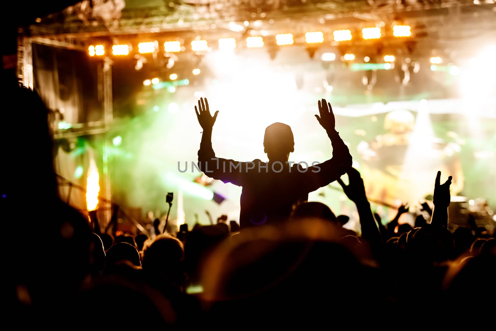 Rock concert, silhouettes of happy people raising up hands