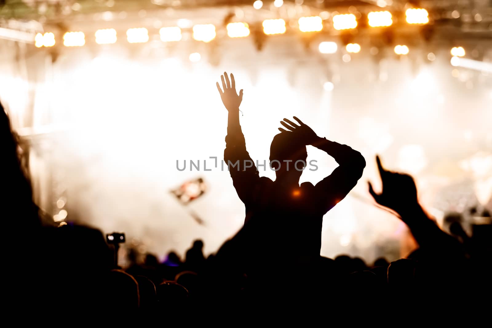 Rock concert, silhouettes of happy people raising up hands