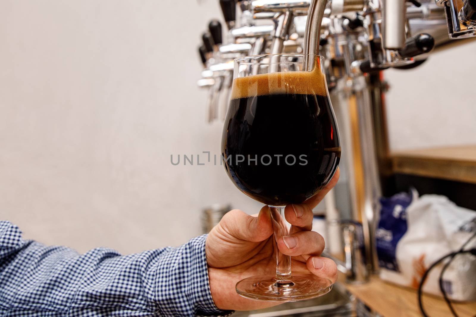 The bartender pours fresh dark beer from tap in the pub