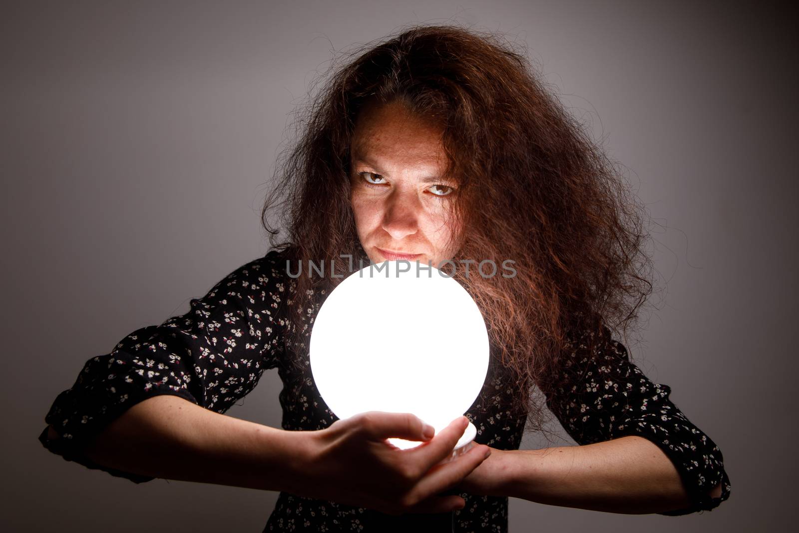 Fortuneteller holding a glowing ball in her hands.