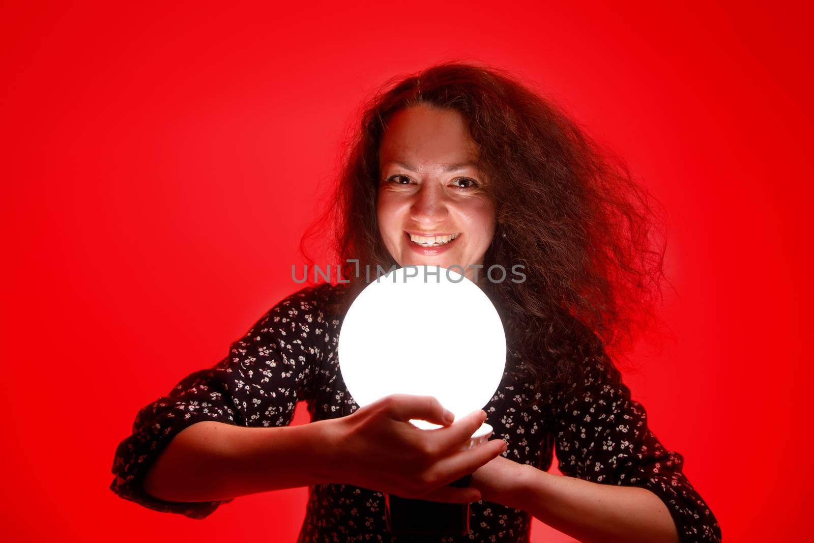 Smiling woman with a luminous ball. Red background