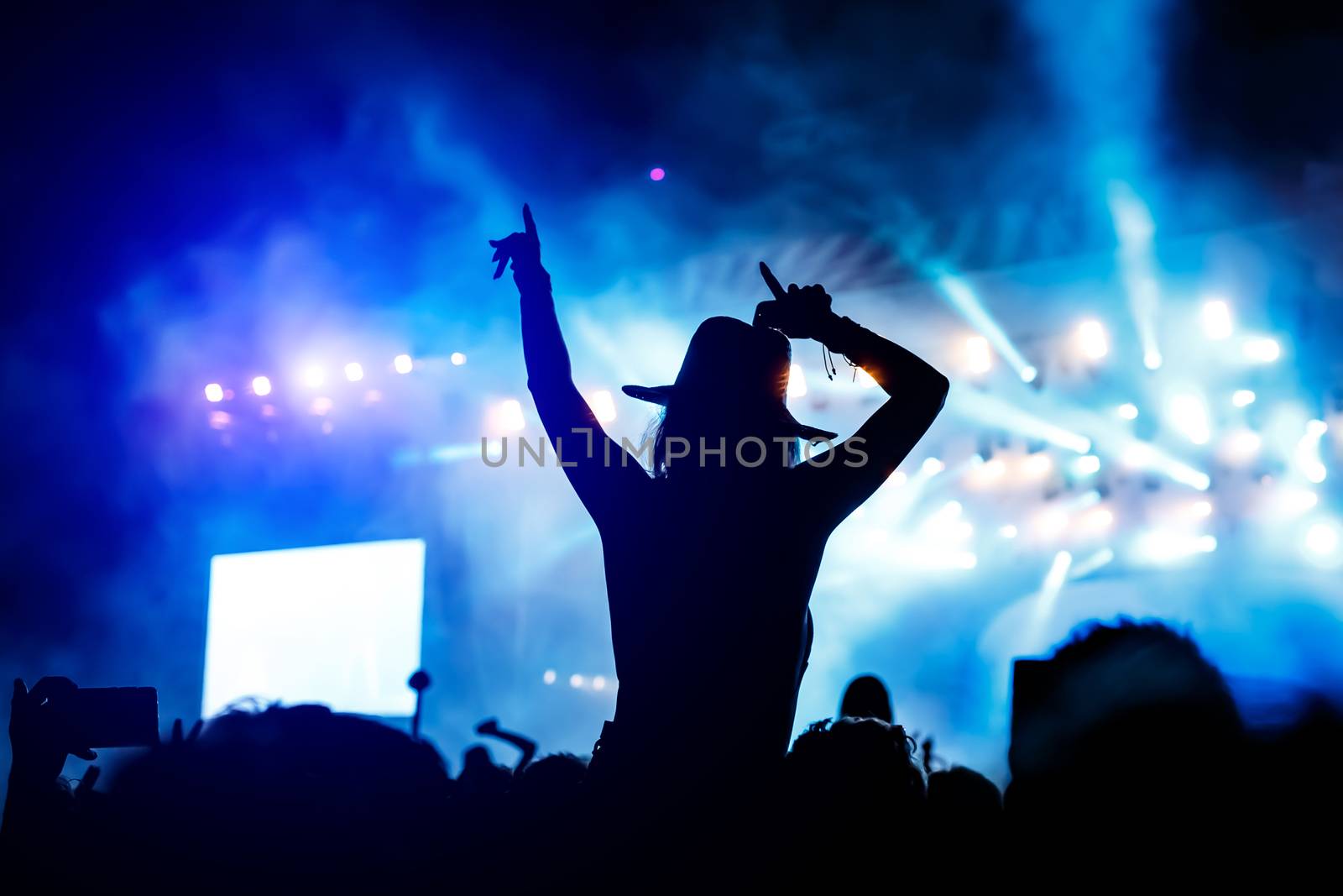 Silhouette of a girl with raised hands at a mass event. Party in a nightclub by 9parusnikov